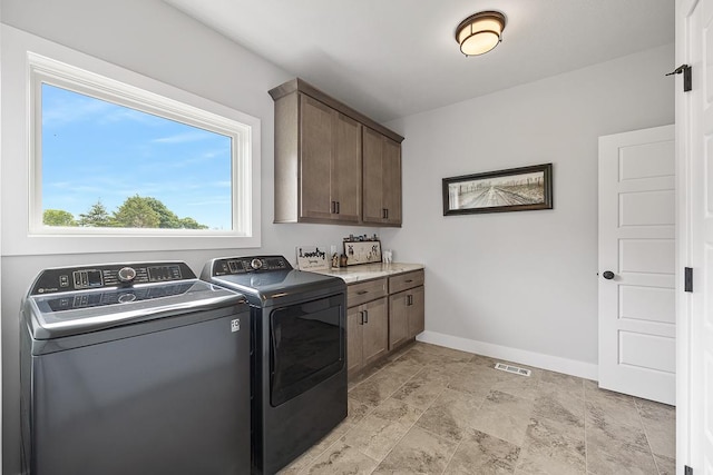 laundry room with washing machine and dryer, cabinet space, visible vents, and baseboards