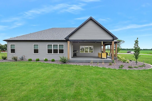 back of property featuring roof with shingles and a yard