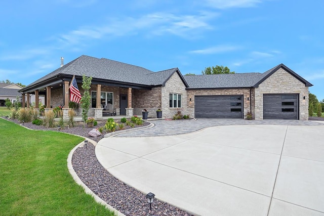 view of front facade with driveway, a shingled roof, an attached garage, covered porch, and a front lawn