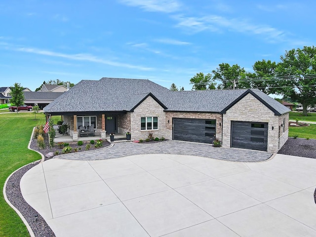 view of front of property with a shingled roof, covered porch, an attached garage, driveway, and a front lawn