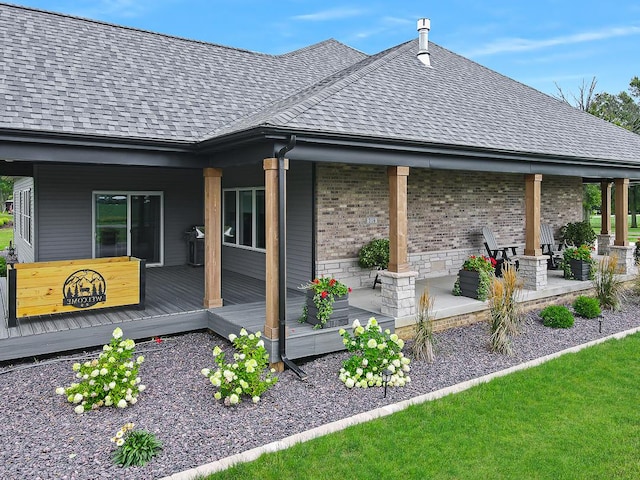 rear view of property with stone siding, brick siding, and roof with shingles