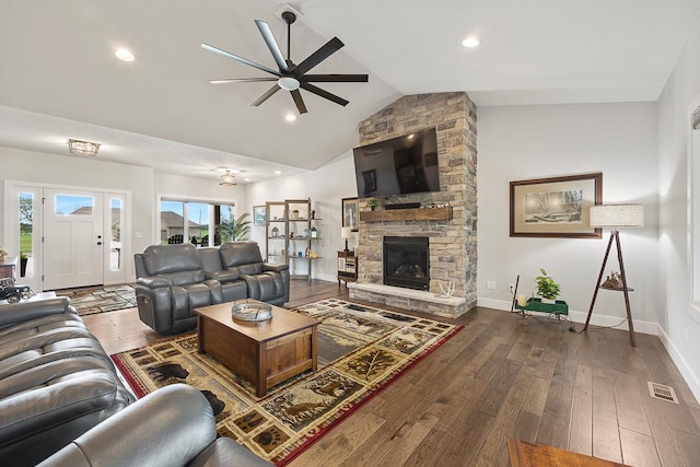 living room with lofted ceiling, wood-type flooring, a stone fireplace, and baseboards