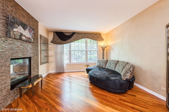 sitting room featuring wood-type flooring and a stone fireplace