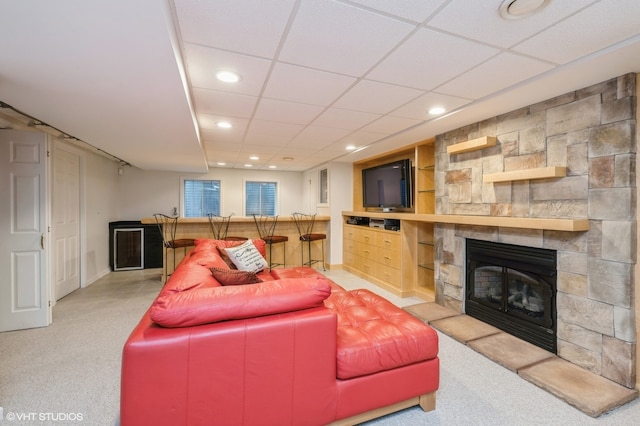 living room with carpet floors, a fireplace, built in features, and a drop ceiling