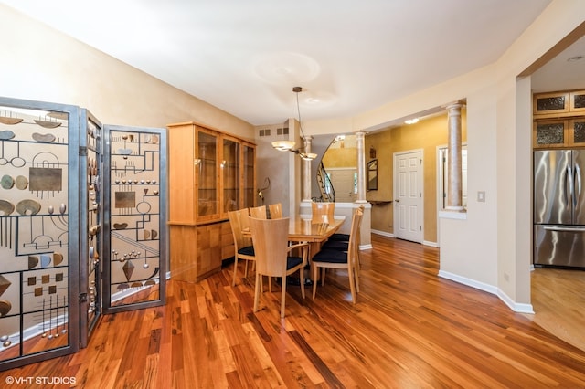 dining space featuring hardwood / wood-style flooring and ornate columns