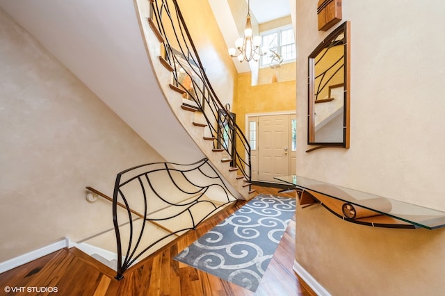 staircase with an inviting chandelier, hardwood / wood-style flooring, and a high ceiling