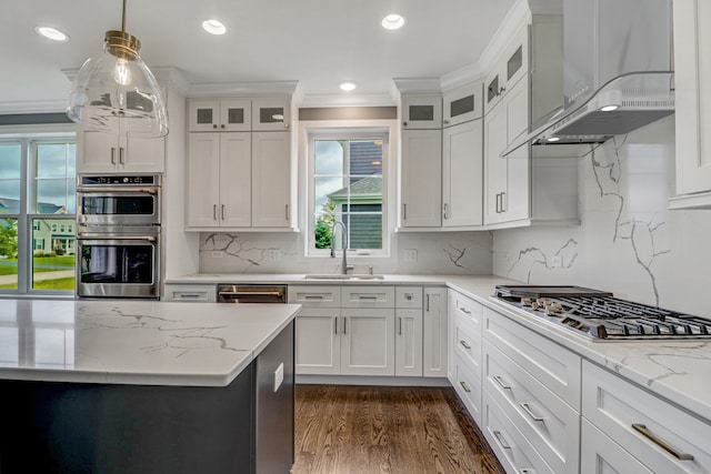 kitchen featuring crown molding, wall chimney range hood, dark wood-type flooring, appliances with stainless steel finishes, and decorative backsplash