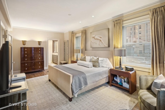 bedroom with light wood-type flooring, ornamental molding, and connected bathroom