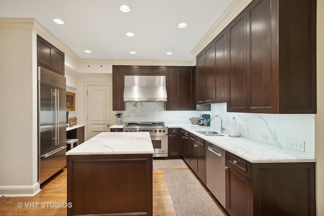 kitchen featuring wall chimney exhaust hood, high quality appliances, light hardwood / wood-style flooring, and a center island