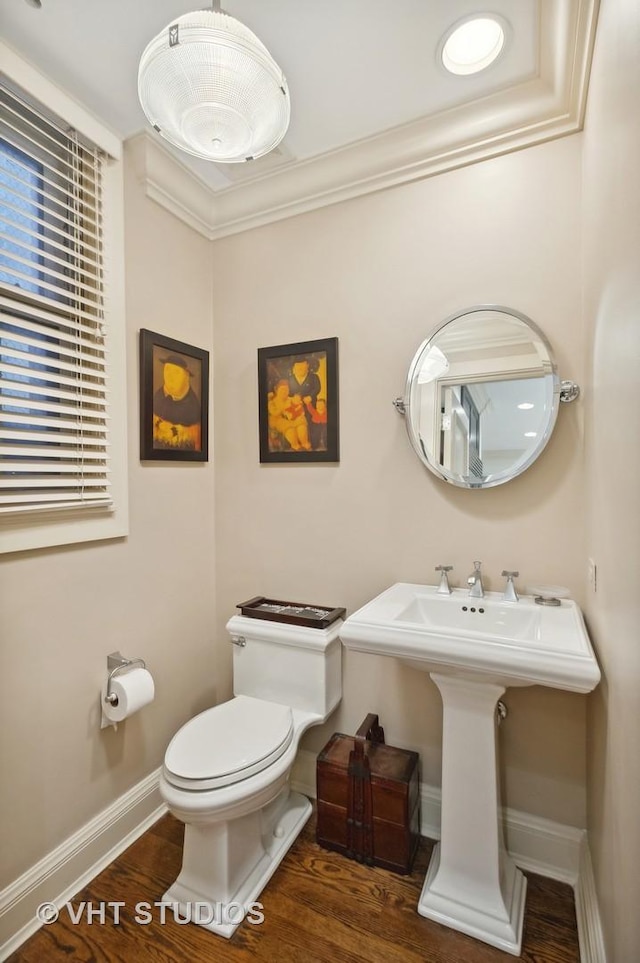 bathroom with hardwood / wood-style flooring, toilet, and crown molding