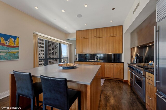 kitchen featuring a center island, a kitchen breakfast bar, sink, dark hardwood / wood-style floors, and premium appliances