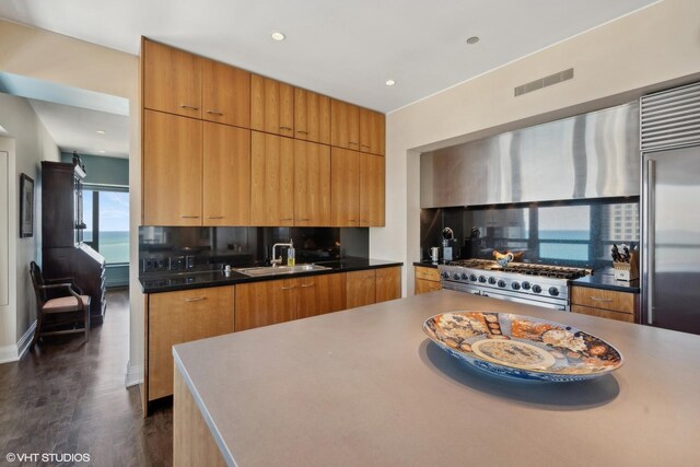 kitchen featuring sink, dark wood-type flooring, backsplash, high quality appliances, and exhaust hood