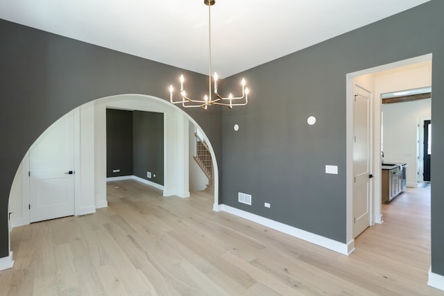 unfurnished dining area with an inviting chandelier and light hardwood / wood-style floors