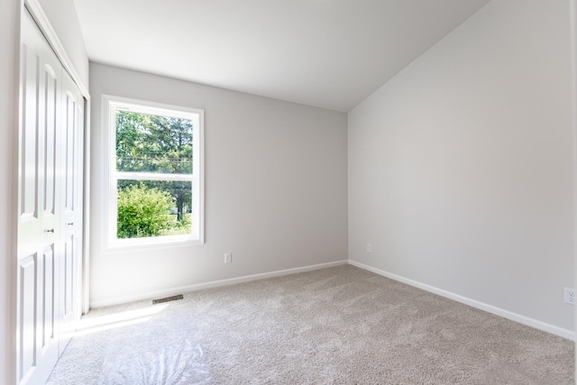 spare room with carpet, visible vents, and baseboards