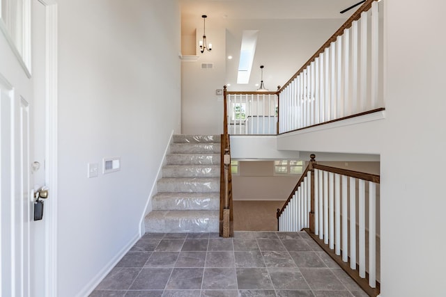 stairs with visible vents, a towering ceiling, and baseboards