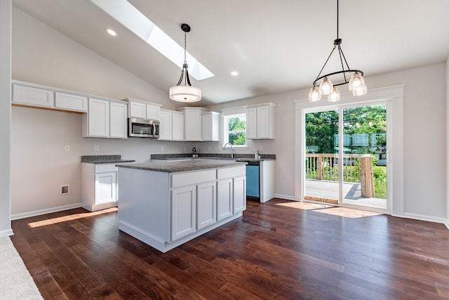 kitchen with dark wood-style flooring, stainless steel microwave, a skylight, and white cabinets