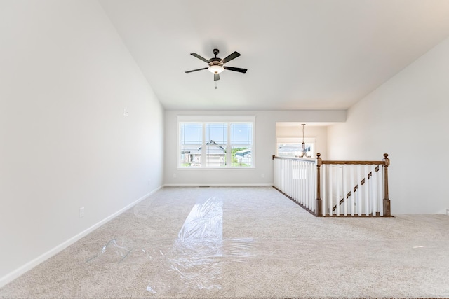 carpeted spare room featuring ceiling fan and baseboards