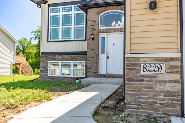 view of exterior entry featuring brick siding and a lawn