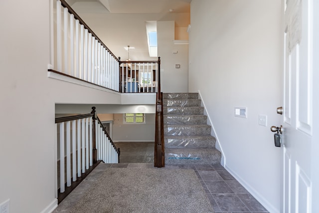 staircase featuring a high ceiling and baseboards