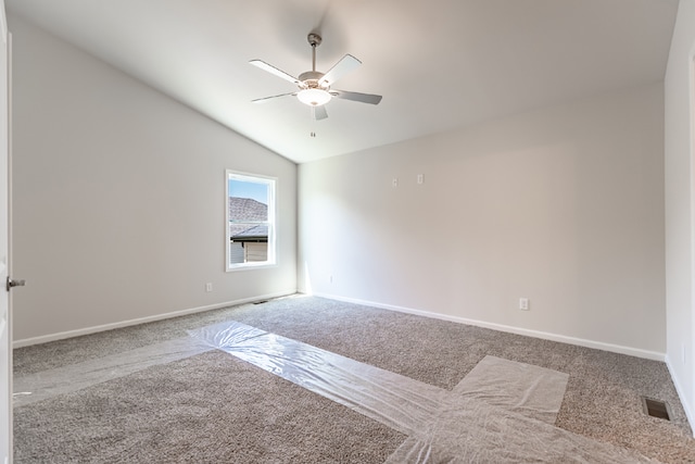 spare room with carpet, visible vents, vaulted ceiling, ceiling fan, and baseboards