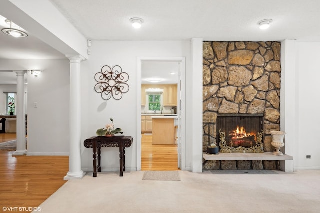 living room with wood-type flooring, a fireplace, a textured ceiling, and ornate columns