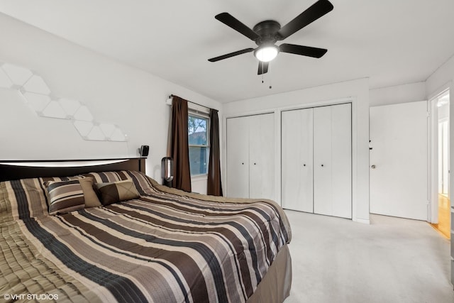 carpeted bedroom with two closets and ceiling fan