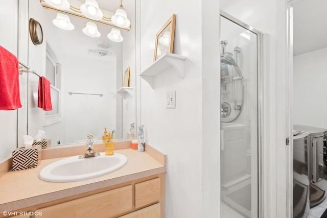 bathroom featuring vanity, a shower with shower door, and washing machine and dryer