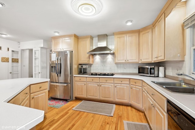 kitchen with sink, black appliances, light brown cabinetry, wall chimney exhaust hood, and light wood-type flooring