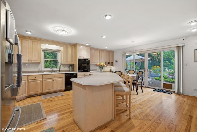 kitchen featuring hanging light fixtures, a center island, light brown cabinets, and black appliances