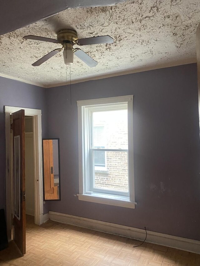 empty room with a textured ceiling, light parquet flooring, and ceiling fan