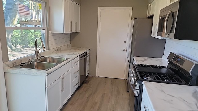 kitchen featuring white cabinetry, sink, backsplash, stainless steel appliances, and plenty of natural light