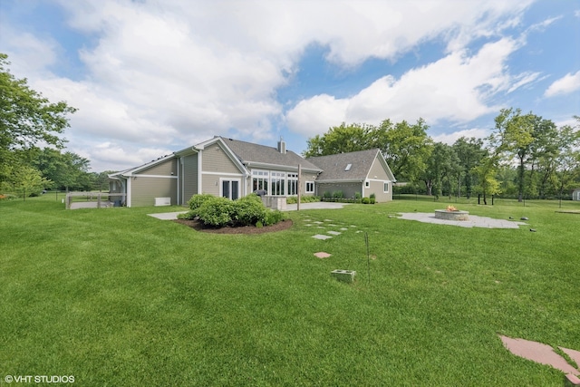 rear view of property with a fire pit, a lawn, and a patio area