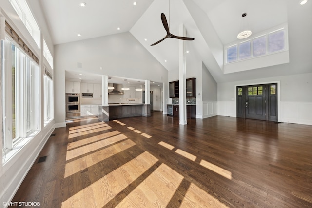 unfurnished living room with high vaulted ceiling, ceiling fan, and dark hardwood / wood-style floors