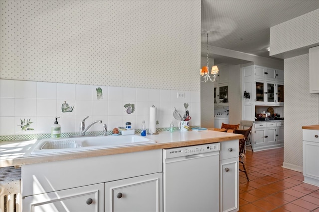 kitchen with white dishwasher, a notable chandelier, backsplash, and white cabinetry