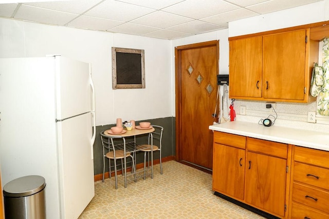 kitchen with decorative backsplash, a paneled ceiling, and white refrigerator