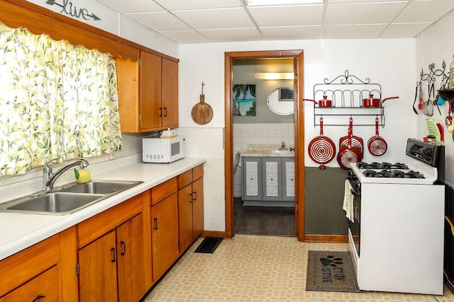 kitchen with a drop ceiling, sink, and white appliances