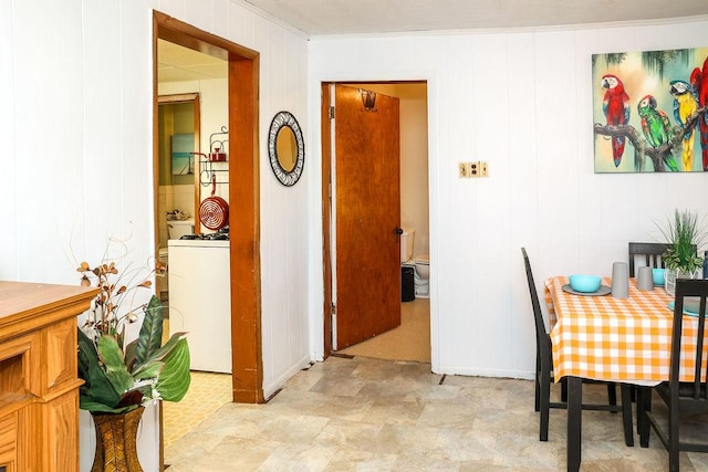 dining area with wood walls, ornamental molding, and washer / clothes dryer