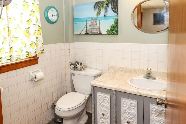 bathroom with toilet, vanity, and tile walls