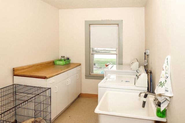 laundry room with sink, washing machine and dryer, and cabinets