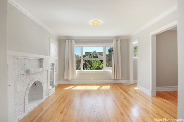 unfurnished living room featuring a brick fireplace, crown molding, and light wood-type flooring