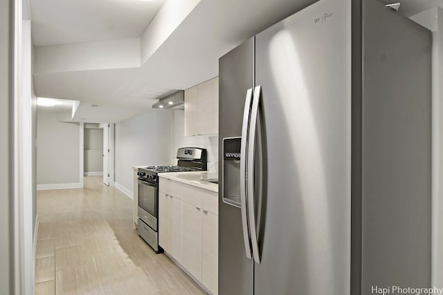 kitchen with light hardwood / wood-style floors, white cabinetry, and stainless steel appliances