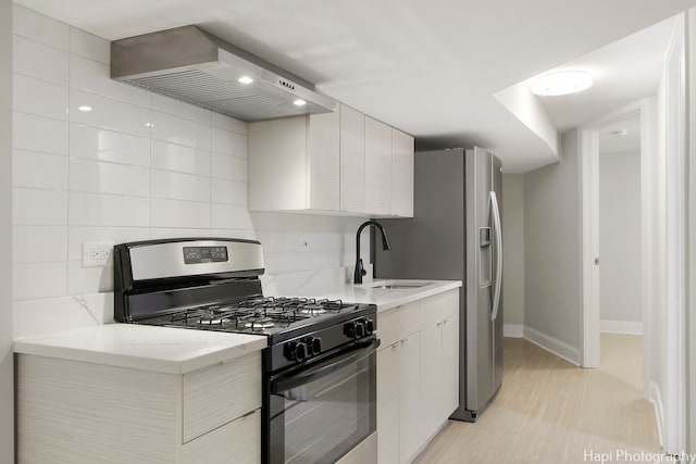 kitchen featuring appliances with stainless steel finishes, wall chimney range hood, sink, light stone countertops, and light tile patterned flooring