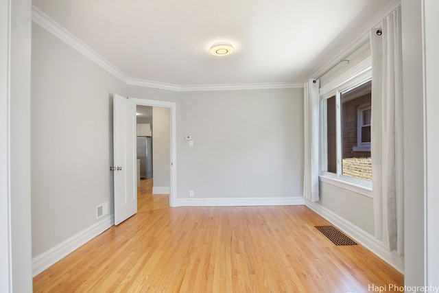 empty room with light hardwood / wood-style floors and ornamental molding