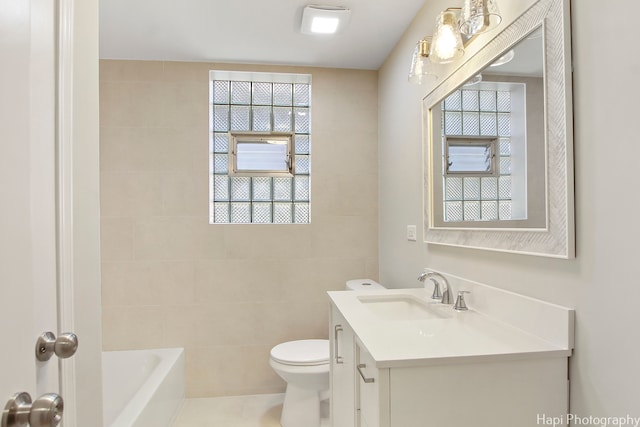 bathroom with tile walls, a healthy amount of sunlight, toilet, and vanity