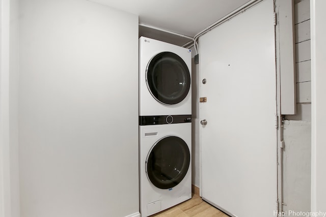 clothes washing area featuring light hardwood / wood-style flooring and stacked washer / dryer