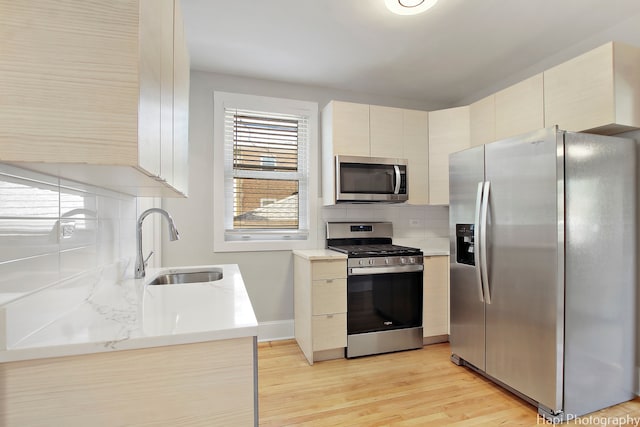 kitchen featuring cream cabinets, stainless steel appliances, light wood-type flooring, sink, and backsplash