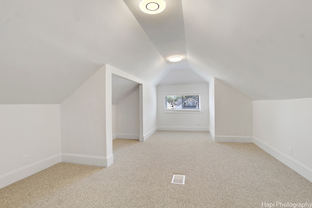 additional living space with light carpet and vaulted ceiling