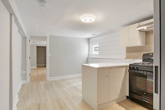 kitchen featuring light wood-type flooring, light stone countertops, light brown cabinetry, wall chimney exhaust hood, and black gas stove