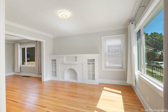 unfurnished living room with a fireplace, crown molding, and light wood-type flooring