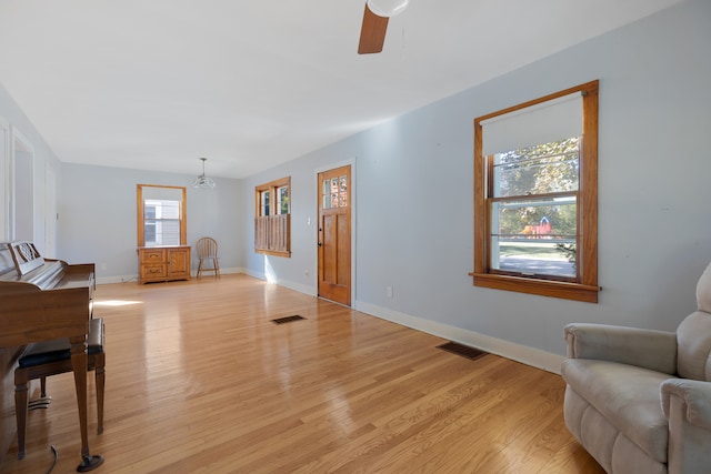 living room featuring light hardwood / wood-style flooring and ceiling fan with notable chandelier